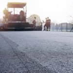 Workers placing new coating of asphalt on the road.