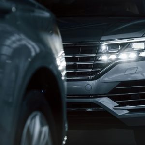 Powerful headlights. Particle view of modern luxury cars parked indoors at daytime.