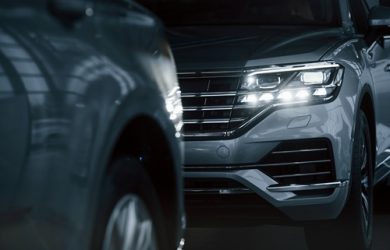 Powerful headlights. Particle view of modern luxury cars parked indoors at daytime.